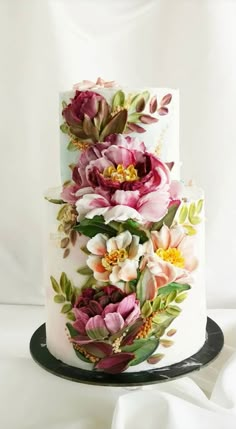 a three tiered cake with flowers painted on it