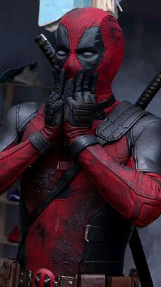 deadpool is standing with his hands on his face