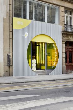 an empty street in front of a building with yellow and white decorations on the windows