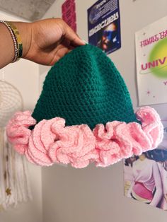 a hand holding a green and pink knitted hat