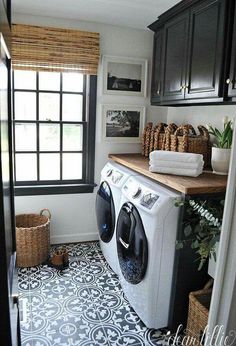 a washer and dryer in a small laundry room with black cabinetry, patterned tile flooring and wooden counter tops