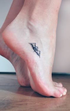 a woman's foot with a lightning bolt tattoo on her left ankle and an arrow in the middle