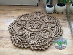 a crocheted rug on the floor next to potted plants