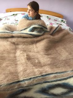 a woman laying in bed under a blanket with an animal print design on it and she is looking at the camera