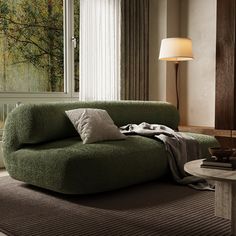 a living room with a green couch, table and lamp on the floor next to it