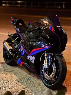 a colorful motorcycle parked on the side of the road at night with its lights on