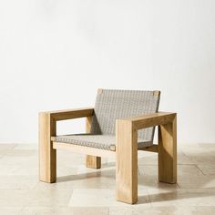 a wooden chair sitting on top of a tile floor next to a white wall in an empty room