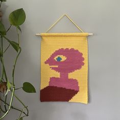 a crocheted wall hanging with an image of a woman's face on it