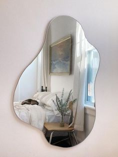 a mirror reflecting a bedroom with a bed in the corner and a painting on the wall