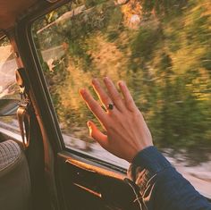 a person's hand on the dashboard of a car with trees in the background