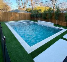 a backyard with artificial grass and a swimming pool surrounded by wooden fenced in areas