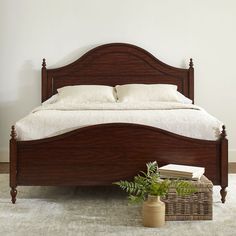 a bed with white linens and pillows in a room next to a basket full of books