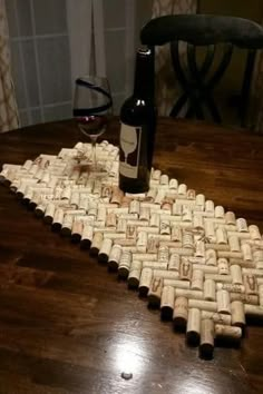 a wine bottle sitting on top of a wooden table next to a cork mat that is shaped like a heart