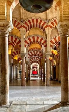 the inside of an ornate building with columns and arches on either side of the walkway