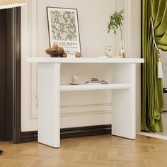 a white table in a room with green drapes on the windowsill and pictures