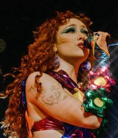 a woman with red hair and tattoos holding a microphone