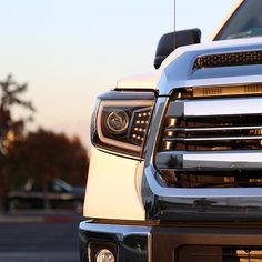 the front end of a white truck parked in a parking lot