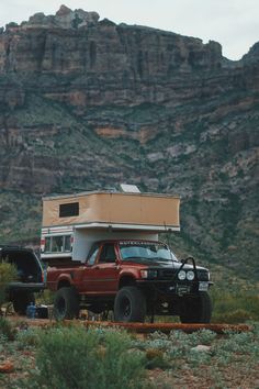 a truck with a camper attached to it parked in front of a mountain