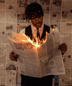 a man reading a newspaper with flames coming out of his face and hands behind him