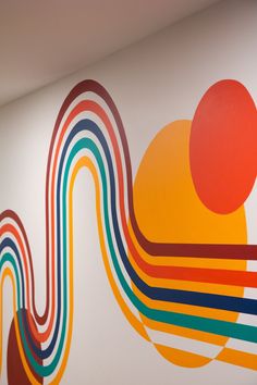 an abstract painting is on the wall next to a white wall with colorful lines and circles painted on it