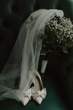 a bride's wedding bouquet and shoes on a green velvet chair with tulle