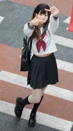 a girl in a school uniform is crossing the street with her hand on her head