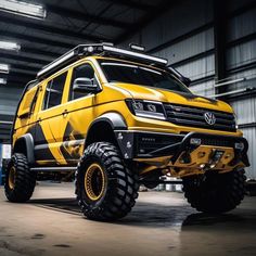 a yellow truck with big tires parked in a garage