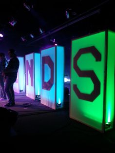 two people standing in front of an illuminated sign that says sndd on it