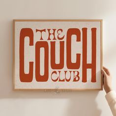 a person holding up a sign that says the couch club on it's wall