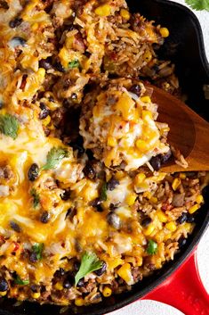 a skillet filled with mexican rice, beans and cheese on top of a table