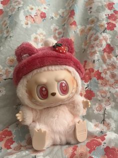 a small stuffed animal with a red hat on it's head sitting on a bed