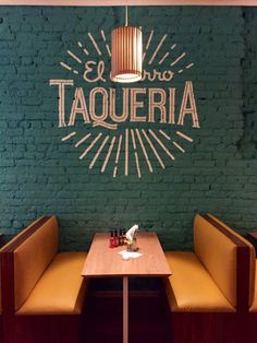 the interior of a restaurant with green brick walls and wooden booths, two yellow benches on each side