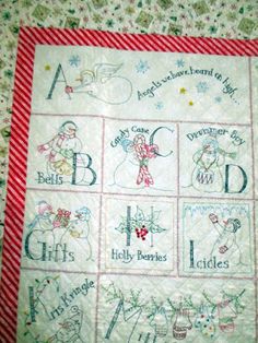 a cross stitched christmas quilt with the letters and numbers on it, including snowmen