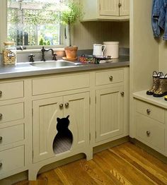 a kitchen with white cabinets and wooden floors has a cat hole in the cabinet door