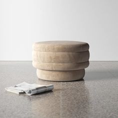 a round stool sitting on top of a floor next to a cell phone and pen