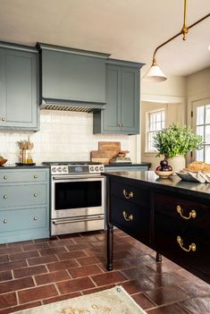 a kitchen with blue cabinets and an island in front of the stove, sink and oven