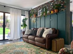 a living room filled with furniture and lots of plants on top of the wall next to a sliding glass door