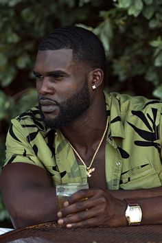 a man sitting at a table with a drink in his hand and looking off to the side