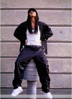 a woman sitting on top of a fire hydrant wearing black pants and white shirt