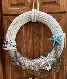 a wreath made out of rope and seashells hanging on a door handle with starfish