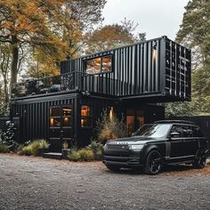 an suv parked in front of a black shipping container home