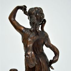 a bronze statue of a woman holding a child's hand with both hands on her head