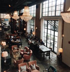 a restaurant with lots of tables and couches in front of large windows that look out onto the street