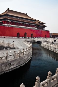 a large building with a red wall next to a body of water