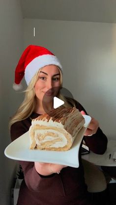 a woman in a santa hat holding a plate with a piece of cake on it