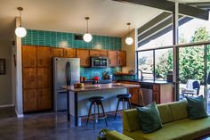 an open kitchen and living room area in a house with green tiles on the walls