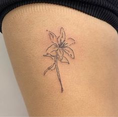 a small flower tattoo on the back of a woman's thigh