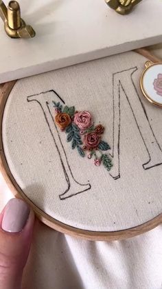 a hand embroidered letter with flowers on it