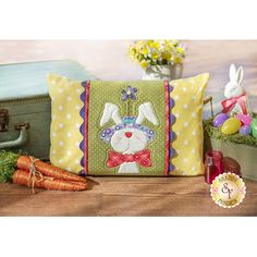 a pillow with a bunny on it next to some carrots and other things in the background