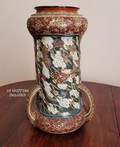 an ornate vase sitting on top of a wooden table next to a white and red wall